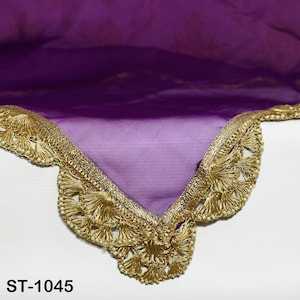 May include: A section of a purple sheer fabric with a gold-coloured, ornate trim. The trim features a scalloped edge with small, round embellishments and tassel-like details. The text "ST-1045" is visible in the lower left corner.