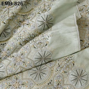 May include: Pale green fabric with intricate embroidery. The design features repeating circular patterns with radial spokes and floral accents in shades of gold, silver, and green. The text "EMB-826" is visible in the upper left corner. The fabric has a subtle sheen.