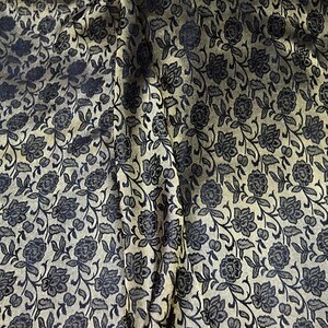 May include: A close-up of a fabric with a black floral pattern on a gold background.