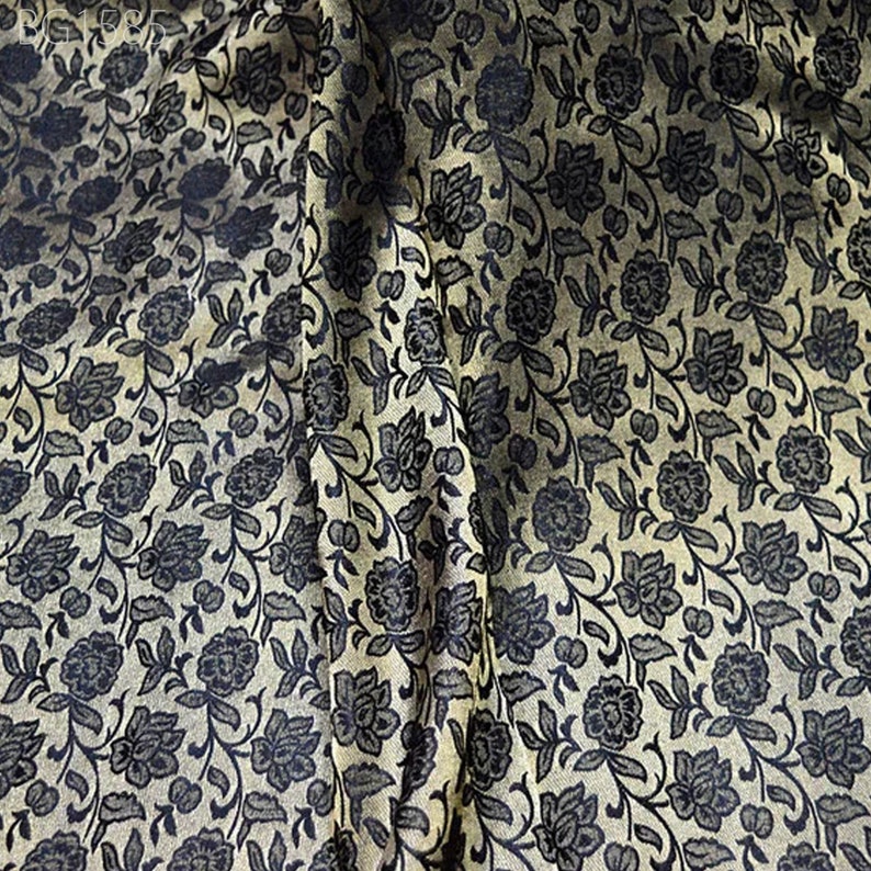 May include: A close-up of a fabric with a black floral pattern on a gold background.