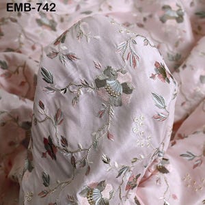 Puede incluir: Primer plano de una tela rosa claro con patrones florales bordados. El bordado presenta flores y hojas en tonos grises, rosas y verdes. La tela tiene un brillo sutil, y el texto "EMB-742" es visible en la esquina superior izquierda.