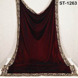 May include: A draped, burgundy velvet shawl with a gold and cream paisley border. The shawl is displayed on a white surface against a patterned background. The text "ST-1263" is visible in the upper right corner.