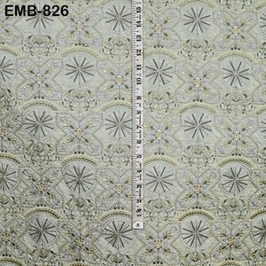 May include: A light green fabric with an intricate embroidered pattern featuring circular and floral designs. A ruler is placed vertically along the fabric, showing measurements in inches. The text "EMB-826" is visible in the upper left corner.