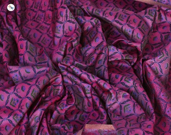 May include: Pink fabric with a blue and green floral pattern. The fabric is folded and has a slight sheen.