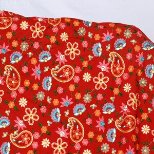 May include: Red fabric with a paisley and floral pattern. The fabric is embroidered with colorful flowers and paisley shapes.