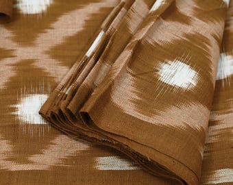 May include: Close-up of folded brown fabric with a white and brown ikat pattern. The fabric has a textured appearance and is layered, showcasing the design. The text "BCG-2888" is in the upper left corner.