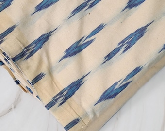 May include: Cream-coloured fabric with a blue ikat pattern. The fabric is folded and the edges are visible. The fabric is labelled "BCG-2809".