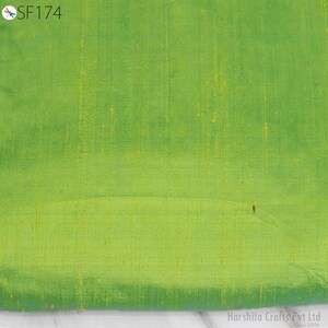 May include: A close-up of a green fabric with a subtle sheen. The fabric has a fine, woven texture and a slightly textured surface.