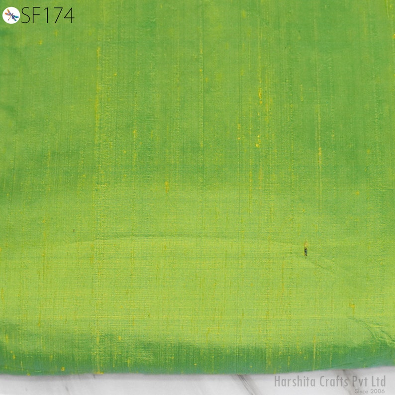 May include: A close-up of a green fabric with a subtle sheen. The fabric has a fine, woven texture and a slightly textured surface.