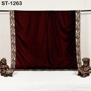 May include: A burgundy velvet textile with ornate gold and black embroidered borders. The textile is draped over a rod, with the text "ST-1263" in the upper left corner. Decorative statues flank the textile.
