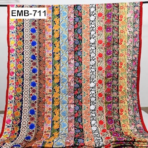 Peut inclure: Un gros plan sur un tissu avec une variété de bordures brodées colorées. Le tissu est de couleur beige clair et les bordures sont toutes de différents motifs et couleurs. Le texte "EMB-711" est visible dans le coin supérieur gauche de l'image.