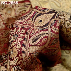 May include: Close-up of a fabric with a detailed paisley pattern. The fabric features a rich burgundy background with gold and black floral and paisley designs. The text "BG-2568" is visible in the upper left corner.