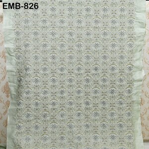 May include: A light green fabric with intricate embroidery. The design features a repeating pattern of star-like shapes and floral motifs. The text "EMB-826" is visible in the upper left corner. The fabric has a delicate, textured appearance, suitable for apparel or home decor.