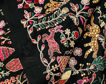 May include: Black fabric with intricate embroidery featuring colorful floral and animal motifs. The design includes pink, red, green, and gold thread, creating a detailed and ornate pattern. The text "EMB-914" is visible in the upper left corner.
