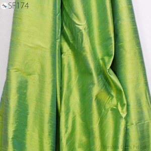May include: A close-up of a green fabric with a subtle sheen. The fabric has a smooth texture and a slightly iridescent quality.
