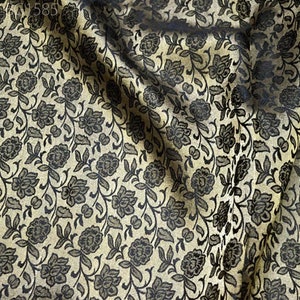 May include: Close-up of a fabric with a black and gold floral pattern. The fabric has a subtle sheen and a soft texture.