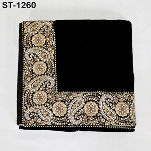 以下が含まれることがあります： 縁に装飾的な刺繍が施された黒色の織物。刺繍は、金、ベージュ、緑の色合いの花柄とペイズリー柄が特徴です。「ST-1260」の文字が左上に表示されています。