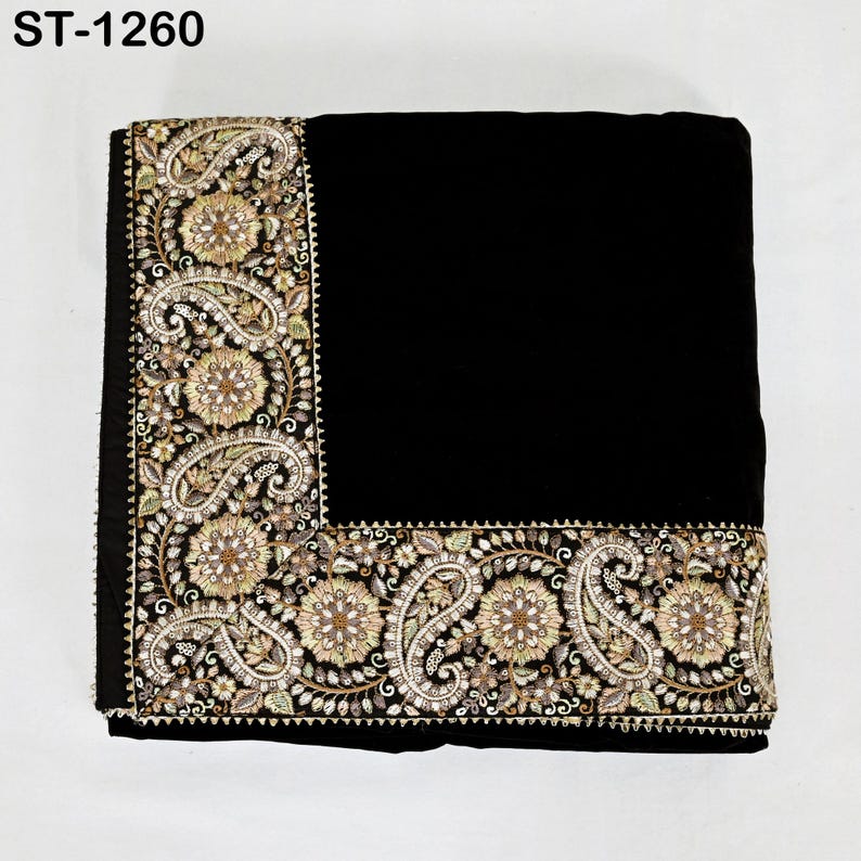 以下が含まれることがあります： 縁に装飾的な刺繍が施された黒色の織物。刺繍は、金、ベージュ、緑の色合いの花柄とペイズリー柄が特徴です。「ST-1260」の文字が左上に表示されています。