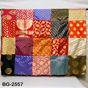 May include: A patchwork quilt with a variety of colorful fabrics, including red, orange, yellow, green, blue, purple, and gold. The quilt is made up of squares of different sizes and patterns. The quilt is labeled "BG-2557".