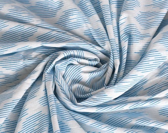 May include: White fabric with a blue and white geometric pattern. The fabric is folded and twisted, showing the pattern from different angles.