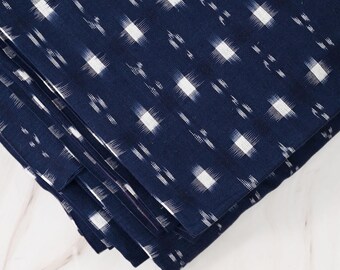 May include: A stack of navy blue fabric with a white ikat pattern. The fabric is folded in thirds and the edges are visible. The fabric is on a white marble surface. BCG-2813