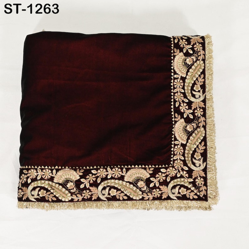May include: A burgundy velvet textile with intricate gold and beige embroidery along the edges. The design includes paisley and floral patterns, with a fringe trim. The text "ST-1263" is in the upper left corner.