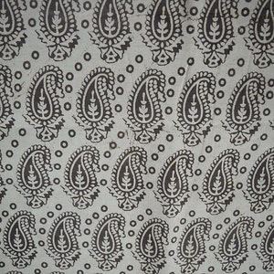 May include: A white fabric with a repeating pattern of black paisley shapes and small circles.
