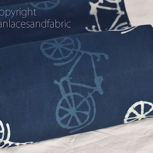 May include: Blue cotton fabric with a white bicycle print. The fabric is folded in half and the print is visible on both sides.