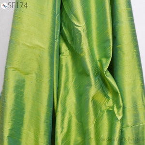 May include: A close-up of a green fabric with a subtle sheen. The fabric has a smooth, silky texture and a slightly iridescent quality.