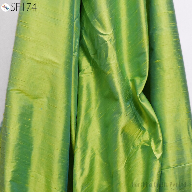 May include: A close-up of a green fabric with a subtle sheen. The fabric has a smooth, silky texture and a slightly iridescent quality.