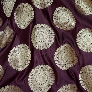 May include: Purple fabric with a repeating pattern of gold circular designs. The designs feature intricate details and a floral motif.