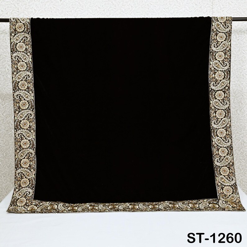 以下が含まれることがあります： 金とクリーム色のペイズリー柄の刺繍が施された、装飾的な縁取りが施された黒いショール。 ショールは白い表面に表示され、下部に「ST-1260」の文字が見えます。