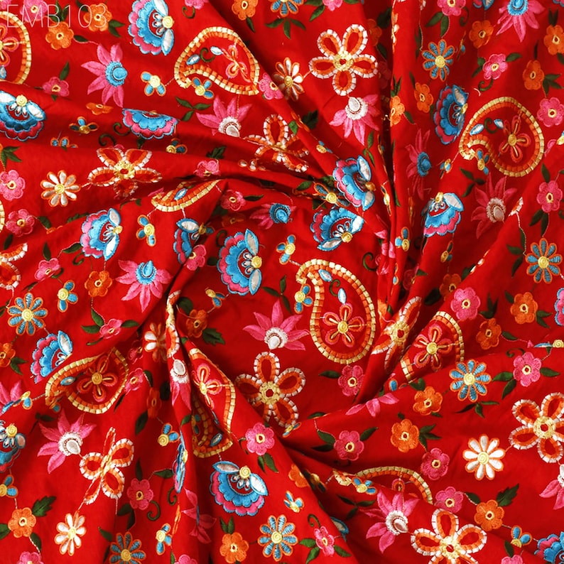 May include: Red fabric with a paisley and floral embroidery pattern. The fabric is a blend of colors including red, pink, blue, yellow, and green.