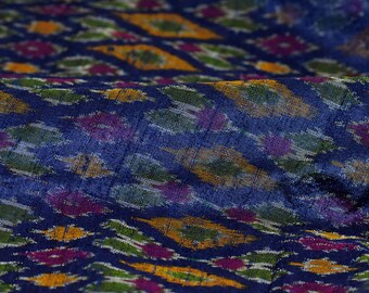 May include: Blue fabric with a colorful ikat pattern. The pattern features yellow, green, pink, and white accents.