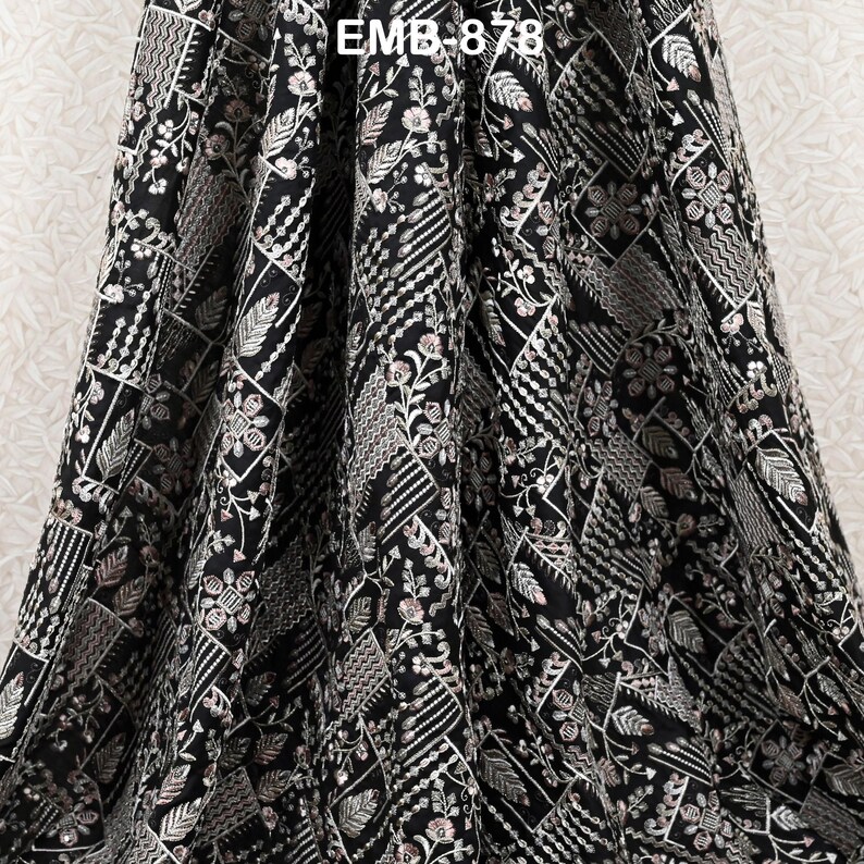 May include: Black fabric with detailed embroidery. The design includes geometric shapes, floral patterns, and leaf motifs in silver and white thread. The text "EMB 878" is visible at the top of the fabric.
