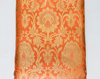 Puede incluir: Tela naranja con un patrón floral dorado. La tela tiene una textura de brocado y es perfecta para proyectos de artesanía o costura.