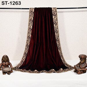May include: A deep burgundy velvet shawl with intricate gold embroidery along the edges. The shawl is draped over a black rod, with the text "ST-1263" visible at the top. Decorative statues flank the shawl.