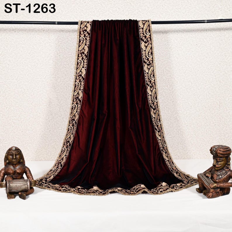 May include: A deep burgundy velvet shawl with intricate gold embroidery along the edges. The shawl is draped over a black rod, with the text "ST-1263" visible at the top. Decorative statues flank the shawl.