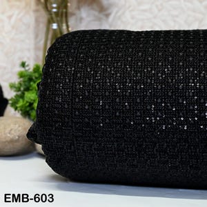 May include: Black fabric with a small, sparkly, grid pattern. The fabric is rolled up and the label "EMB-603" is visible at the bottom of the image.