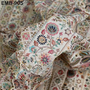 Op de afbeelding: Crèmekleurige stof met ingewikkelde bloemenborduurwerk in roze, blauw, groen en goud. Het ontwerp bevat gedetailleerde bloem- en bladpatronen, met de tekst "EMB-905" zichtbaar linksboven.