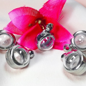 May include: Five silver-toned metal charms with clear glass domes. The charms have a loop at the top for attaching to a necklace or bracelet.