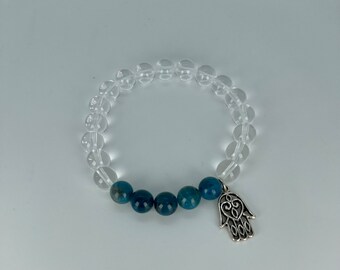 May include: A clear quartz bracelet with blue apatite beads and a silver hamsa charm.