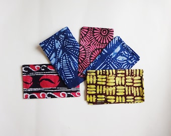 May include: Five fabric squares with different patterns. The squares are in shades of blue, pink, yellow, and brown. The patterns include geometric shapes, flowers, and abstract designs.