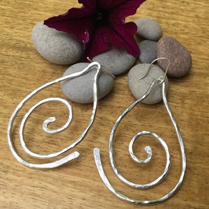 May include: A pair of silver teardrop-shaped earrings with a hammered finish and a spiral design.