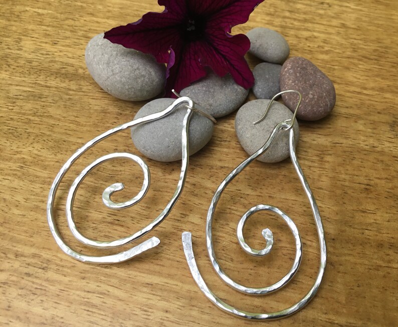 May include: A pair of silver teardrop-shaped earrings with a hammered finish and a spiral design.