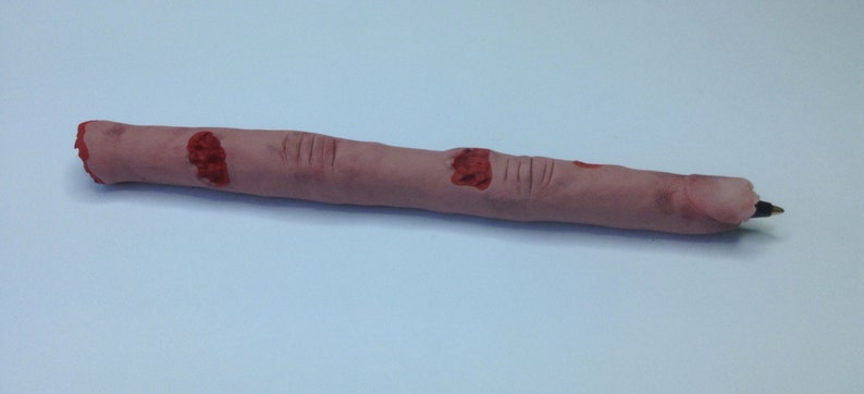 May include: A realistic-looking finger pen with red blood splatter details. The pen is made of a soft, fleshy material and has a black ink tip.