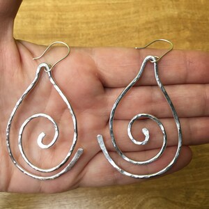 May include: A pair of silver teardrop-shaped earrings with a hammered texture and a spiral design.
