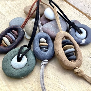 Puede incluir: Cinco collares con diferentes colgantes de piedra y cuentas. Cada collar tiene un cordón de cuero marrón. Los colgantes están hechos de varios materiales, incluyendo madera, piedra y metal.