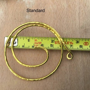 May include: A gold-colored metal hoop with a hammered texture, measuring approximately 7 inches in diameter. The hoop is shown next to a measuring tape.