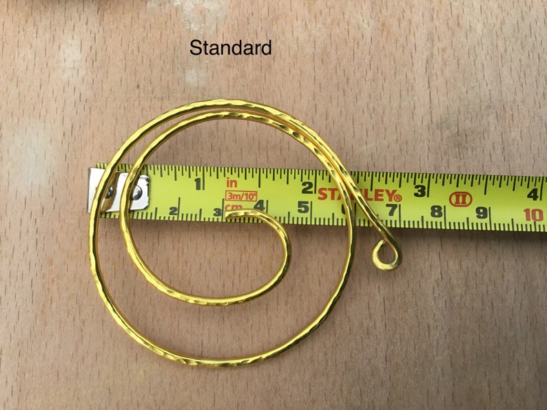 May include: A gold-colored metal hoop with a hammered texture, measuring approximately 7 inches in diameter. The hoop is shown next to a measuring tape.